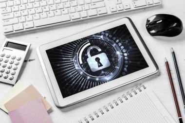 Ofis eşyalarıyla iş yeri ve ekranda asma kilit simgesi olan tablet