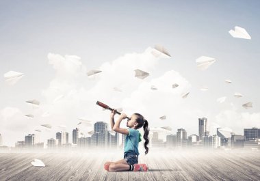 Ahşap zemin ve etrafında uçan kağıt uçaklar üzerinde oturan sevimli kız