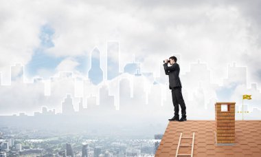 Genç işadamı dürbünüyle şehir manzarasını izliyor. Karışık ortam