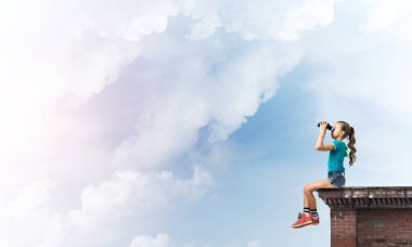 Dürbünle bakan, okul çağındaki sevimli kız çatıyı inşa ediyor.