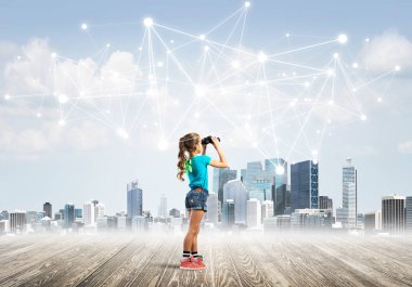 Şirin kız ahşap bir zeminde duruyor ve dürbünle izliyor.