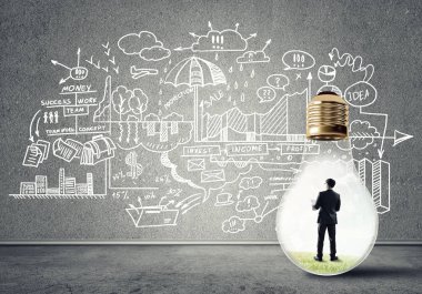 Boş beton odada ampulün içindeki iş adamı ve duvardaki çizimler