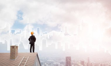 Takım elbiseli genç işadamı ve çatıda kask var. Karışık ortam