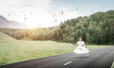 Genç adam gözleri koruma kapalı ve seyir ile güzel ve nefes kesici manzara arka plan üzerinde bulut yukarıda yolun üzerinde meditasyon sırasında konsantre.