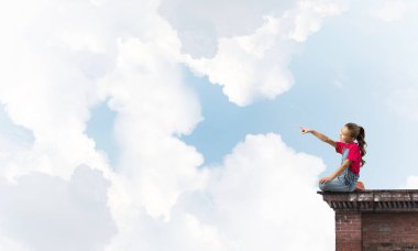 Üstte oturan ve bir şeyi işaret eden sevimli bir kız.
