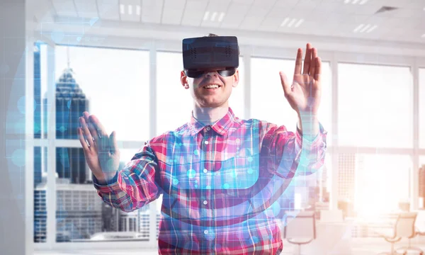 Guy wearing checked shirt and virtual headset working with media screen panel