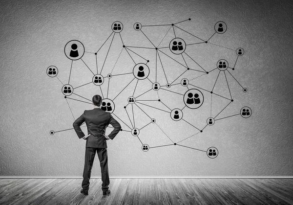 Arkadan görünüşü çizilmiş sosyal bağlantı kavramı ile duvara bakarak işadamı