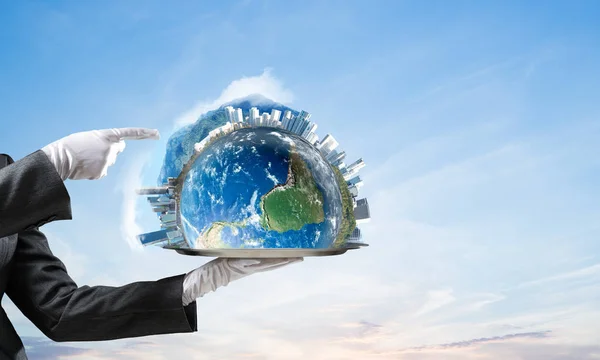 Cropped image of waitress\'s hand in white glove presenting Earth globe on metal tray and pointing on it with cloudy skyscape on background. 3D rendering. Elements of this image are furnished by NASA.
