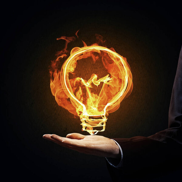 Close of businessman hand holding glowing fire light bulb icon