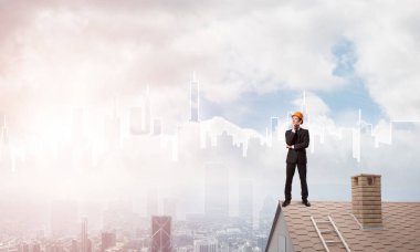 Takım elbiseli genç işadamı ve çatıda kask var. Karışık ortam