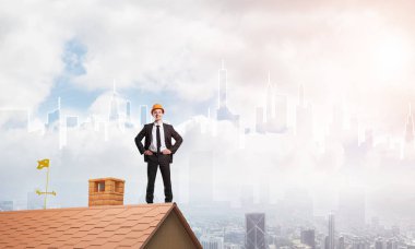 Takım elbiseli genç işadamı ve çatıda kask var. Karışık ortam