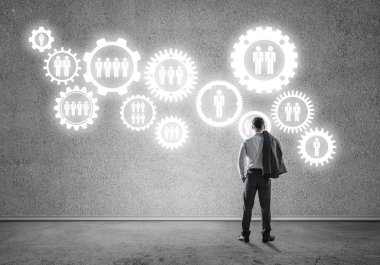 İş adamının çizilmiş dişli mekanizmasıyla duvara baktığı arka plan