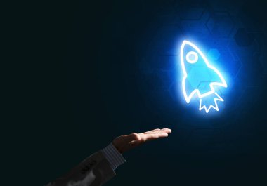 Koyu arkaplanda parlayan roket simgesi ve iş adamı eli