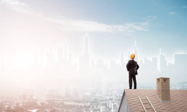 Takım elbiseli genç işadamı ve çatıda kask var. Karışık ortam