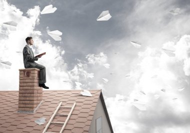 Elinde kırmızı kitap ile ev oturan genç işadamı