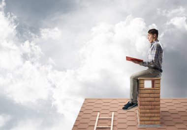 Elinde kırmızı kitap ile evin baca rahat oturan genç adam