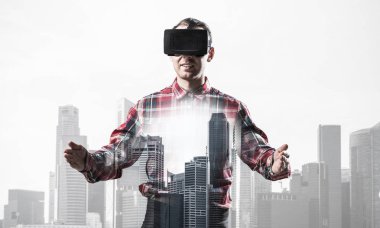 Sanal gerçeklik kulaklığı olan genç bir adam ya da şehrin arka planında 3 boyutlu gözlüklü.