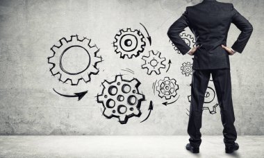 İş adamının çizilmiş dişli mekanizmasıyla duvara baktığı arka plan