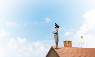 Evin çatısında baş durmak yerine kamerayla zum yapan yüzsüz iş kadını.