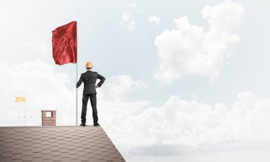 Çatıda duran ve elinde kırmızı bayrak tutan bir iş adamı. Karışık ortam