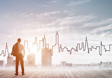 İşadamı arkasını dönüp modern iş merkezinin siluetine bakıyor.