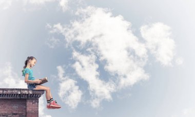 Çatı ve kitap okumak binasında oturan sevimli kız