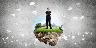 Yeşil yüzen adada beton zemine karşı duran kendine güvenen zarif iş adamı.