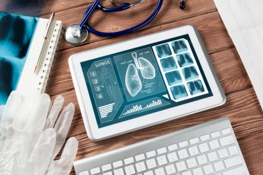 Beyaz tablet bilgisayar ve doktor aletleri ahşap masada.