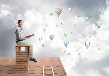 Elinde kırmızı kitap ile evin baca rahat oturan genç adam