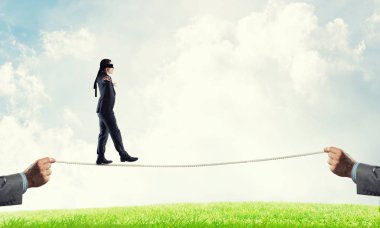 Gözleri bağlı iş adamı halatla doğal arka planda yürüyor.