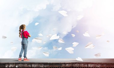 Sevimli kız etrafında uçan çatı ve kağıt uçaklar binasında ayakta