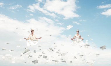 Genç çift gözleri koruma kapalı ve seyir kağıt uçaklar hava bulutlu gökyüzü ile arka plan üzerinde uçan arasında meditasyon sırasında konsantre.