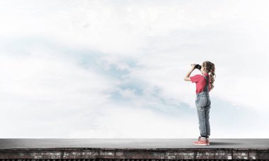 Dürbünle bakan, okul çağındaki sevimli kız çatıyı inşa ediyor.