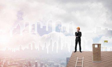 Takım elbiseli genç işadamı ve çatıda kask var. Karışık ortam