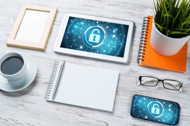 Ofis eşyalarıyla iş yeri ve ekranda asma kilit simgeleri olan tablet