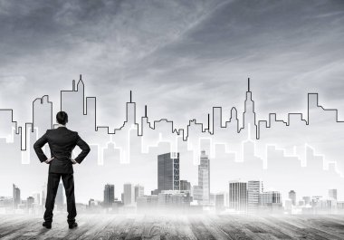 İşadamı arkasını dönüp modern iş merkezinin siluetine bakıyor.