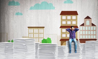 Casual giyim arka plan üzerinde kabataslak cityscape manzaralı belgeleri yığını üzerinde oturan çekici bir adam. Karışık teknik.