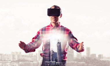 Sanal gerçeklik kulaklığı olan genç bir adam ya da şehrin arka planında 3 boyutlu gözlüklü.