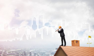 Takım elbiseli genç işadamı ve çatıda kask var. Karışık ortam