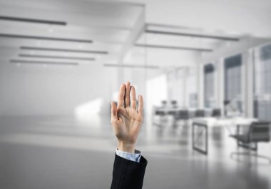 İş kadınının eli ekranda kapalı ve arka planda avuç içi ve ofis