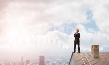 Takım elbiseli genç işadamı ve çatıda kask var. Karışık ortam