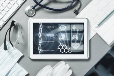 Gri yüzeyde beyaz tablet ve doktor araçları
