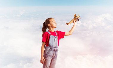 Elinde retro uçak modeliyle tulumlu şirin bir kız çocuğu.