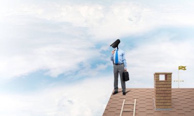 Evin çatısında baş durmak yerine kamerayla zum yapan yüzü olmayan bir iş adamı.