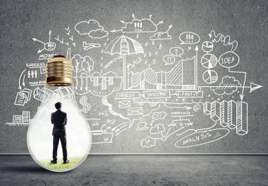 Boş beton odada ampulün içindeki iş adamı ve duvardaki çizimler