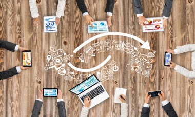 Ellerinde cihazlar bulunan bir grup insan, iletişim ve ağın sembolü olarak birlikte çalışıyor.