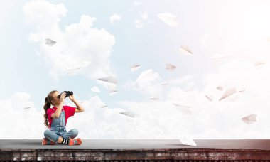 Dürbünle bakan, okul çağındaki sevimli kız çatıyı inşa ediyor.