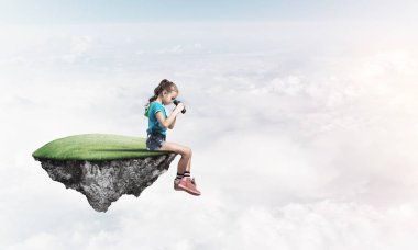 Gökyüzünde yüzen bir adada oturan tatlı, gülümseyen bir kız.