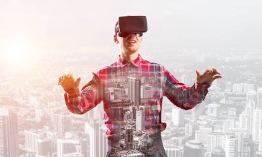 Sanal gerçeklik kulaklığı olan genç bir adam ya da şehrin arka planında 3 boyutlu gözlüklü.