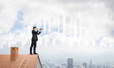 Çatıda takım elbiseli genç bir işadamı var. Karışık ortam